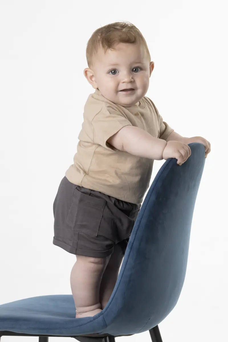 Bambino piccolo in piedi su sedia in studio fotografico a Milano, esempio di shooting con bambini nella fase esplorativa 12-18 mesi
